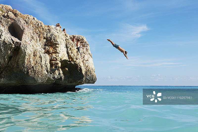 男人从岩石上跳入海中图片素材