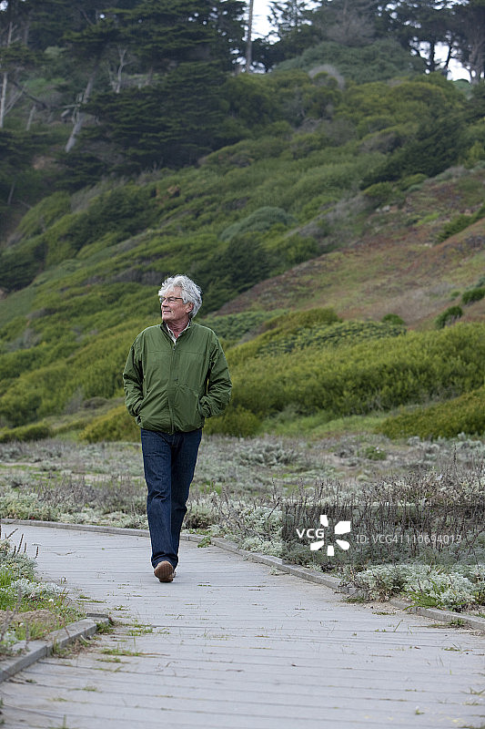 沿着自然小径行走的年长男人图片素材