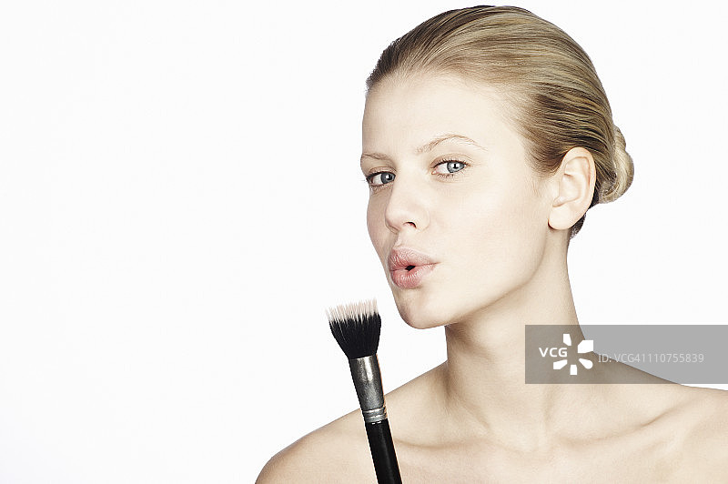 女人对着化妆刷吹气图片素材