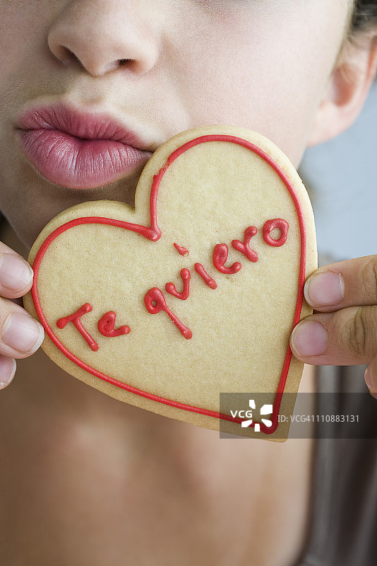 女子撅嘴拿着心形饼干图片素材
