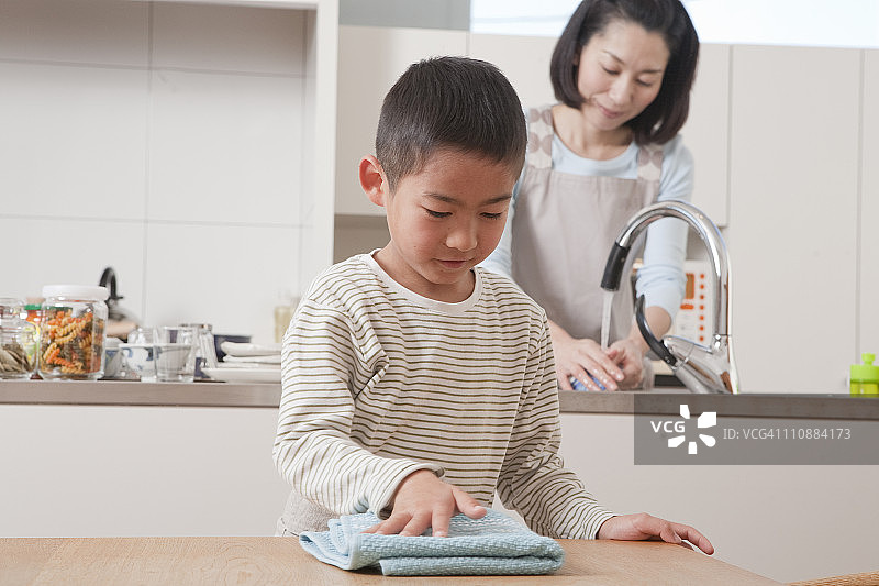 男孩用掸子擦拭桌子图片素材