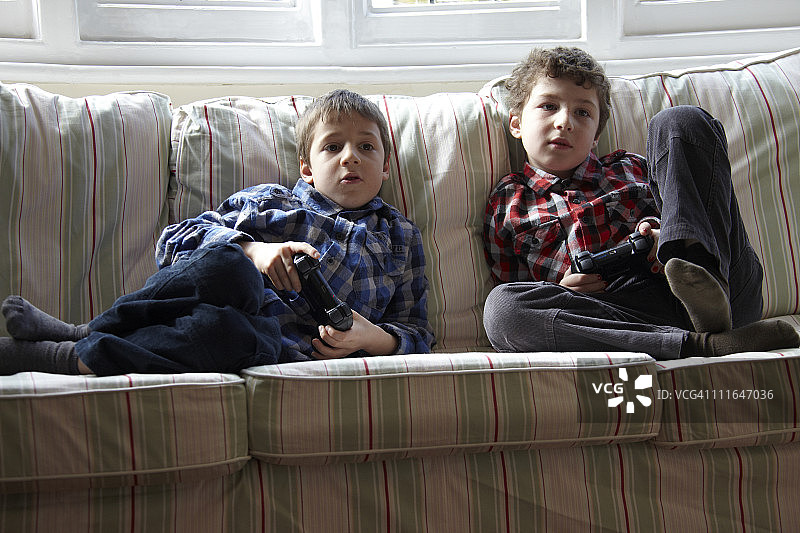 两个男孩在沙发上玩电子游戏图片素材