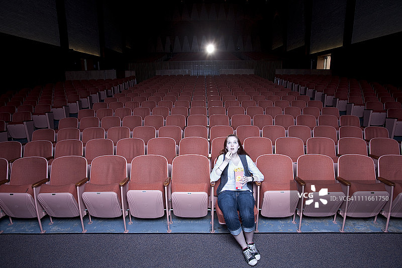 在空旷的剧院里看电影的白人妇女图片素材