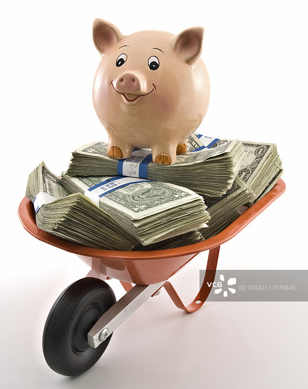 装满钱的手推车上的小猪存钱罐图片素材