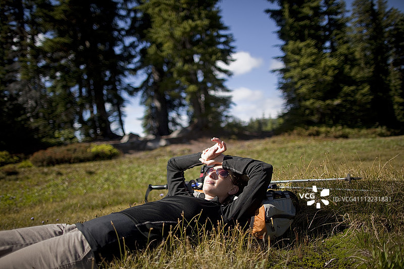 年轻女子在俄勒冈州北部喀斯喀特山脉的杰斐逊公园徒步后休息图片素材