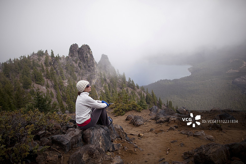 年轻女人在新伯里火山边缘徒步旅行后休息，该火山位于俄勒冈州本德附近的喀斯喀特山脉东部图片素材