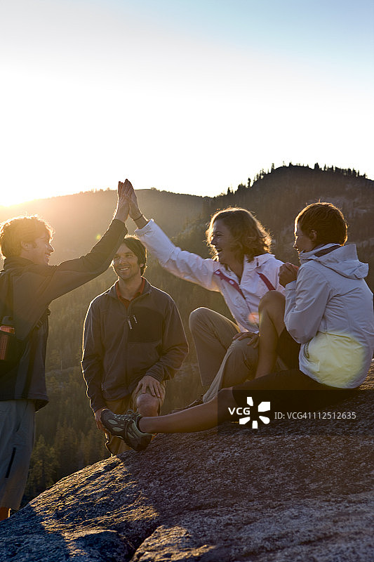 朋友们在山中日落时击掌图片素材