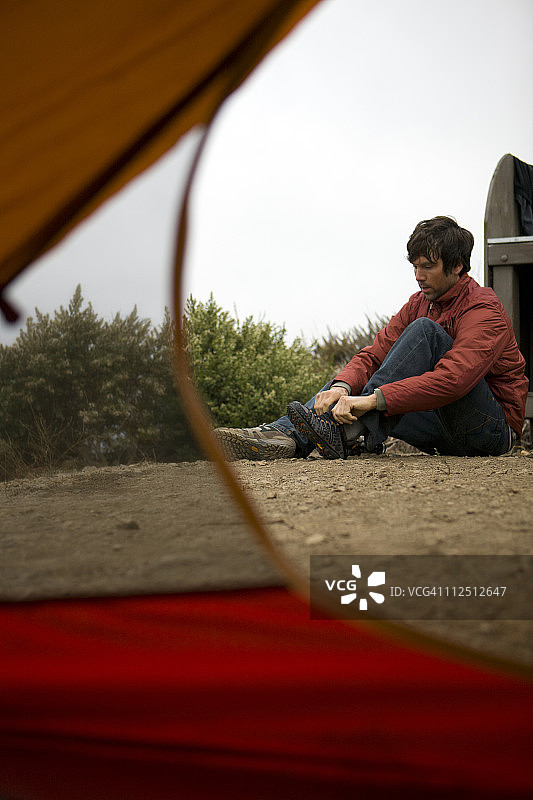 清晨，男子在露营地系鞋带图片素材