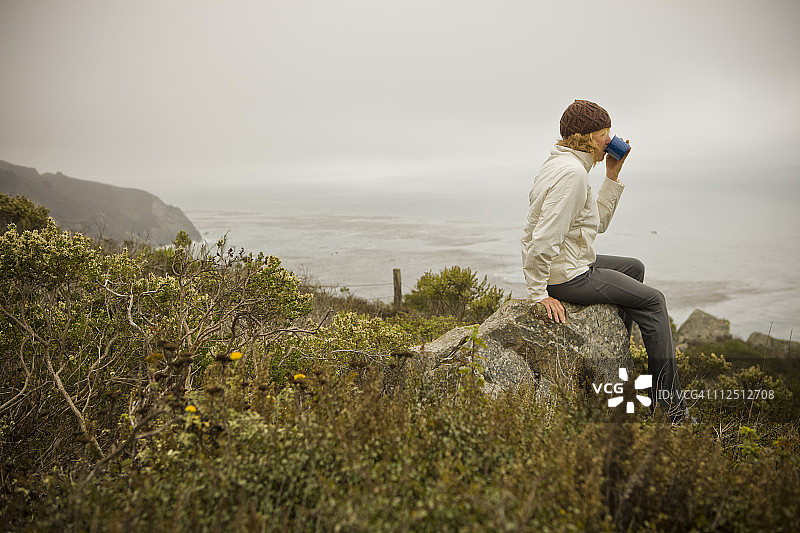 手持咖啡杯欣赏海景的女人图片素材