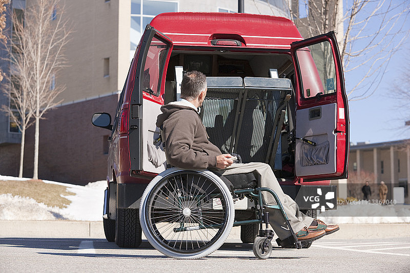 坐轮椅的脊髓损伤男子用遥控器关闭无障碍厢型车的升降门图片素材