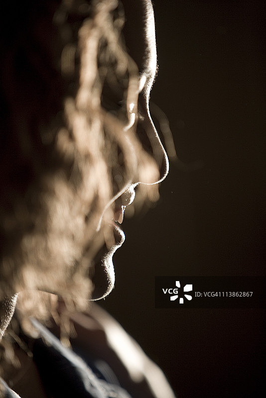 暗室中年轻女子微笑剪影侧面照图片素材