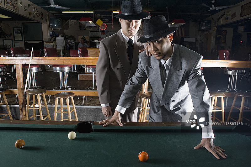 两位戴着帽子和西装的男士站在台球桌旁的肖像图片素材
