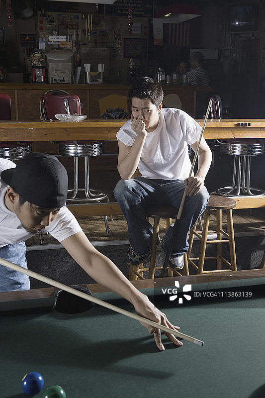 两名男子身穿牛仔裤和T恤打台球图片素材