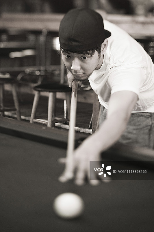 穿着牛仔裤和T恤打台球的年轻男人图片素材