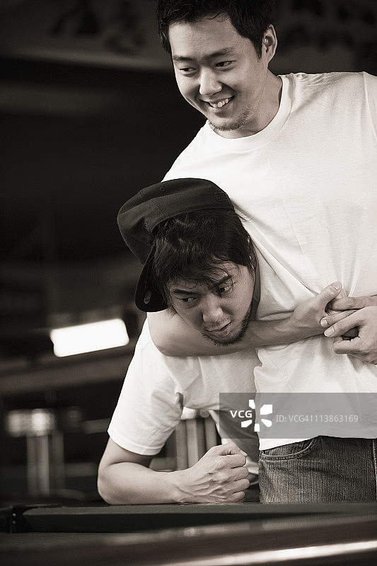 两个穿着牛仔裤和T恤的年轻男人在打架图片素材