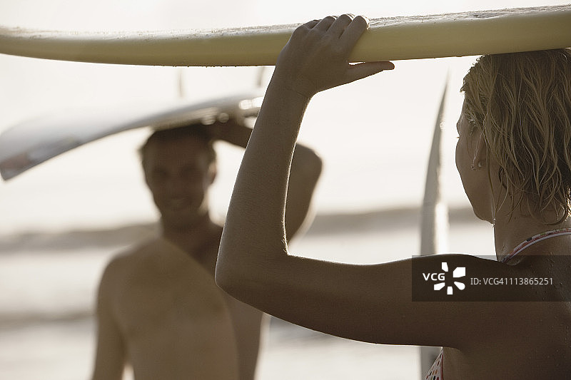 冲浪者和女孩站在海滩上，手持冲浪板图片素材