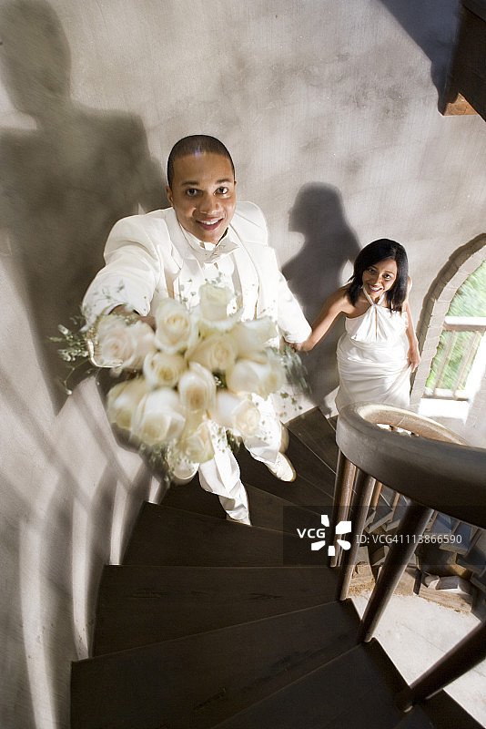 身穿白色礼服的新娘和新郎爬上螺旋楼梯图片素材