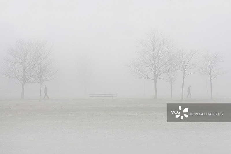 在雾中朝相反方向行走的两人图片素材