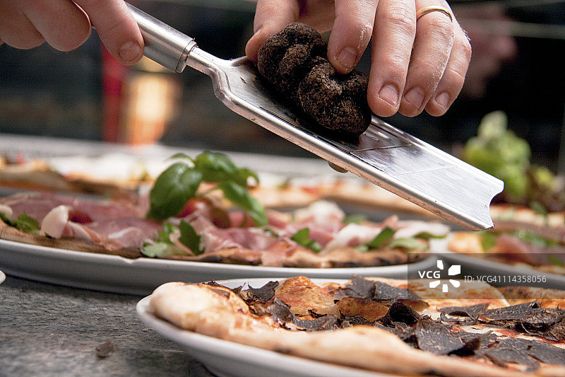 厨师在披萨上刨松露的特写图片素材