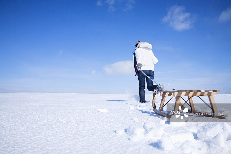 冬季里拉着雪橇的年轻亚洲女子图片素材