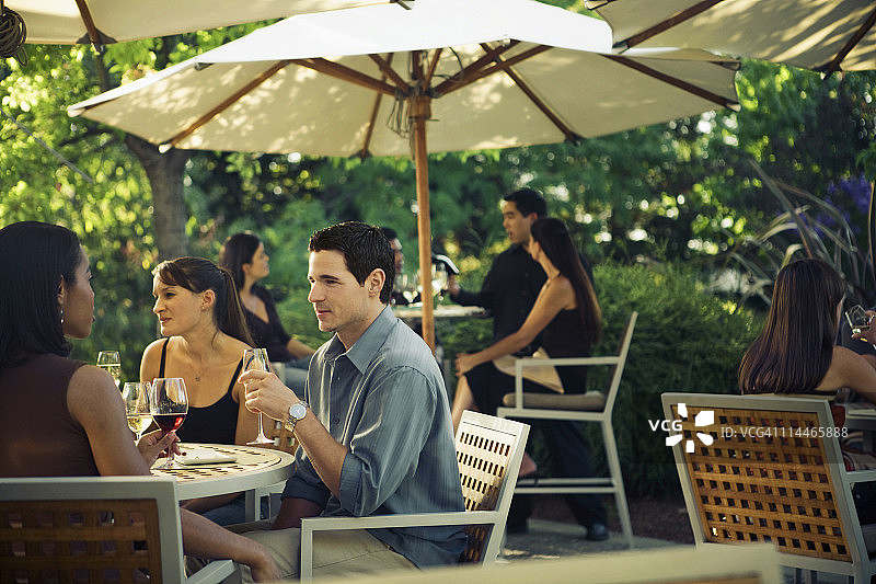 男人与朋友坐在户外餐桌旁图片素材