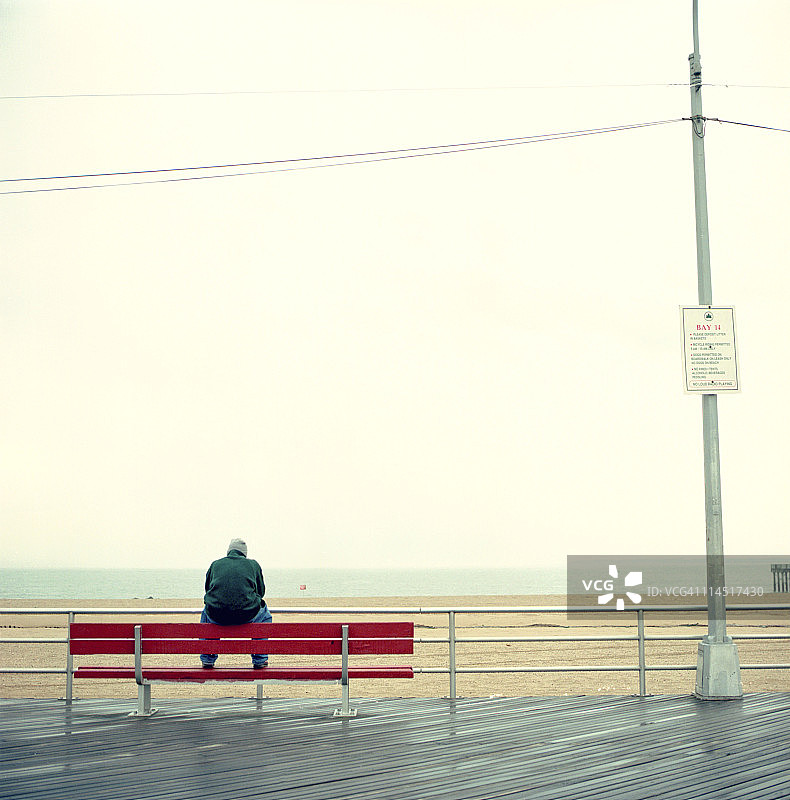 男人独自坐在康尼岛木板路上图片素材