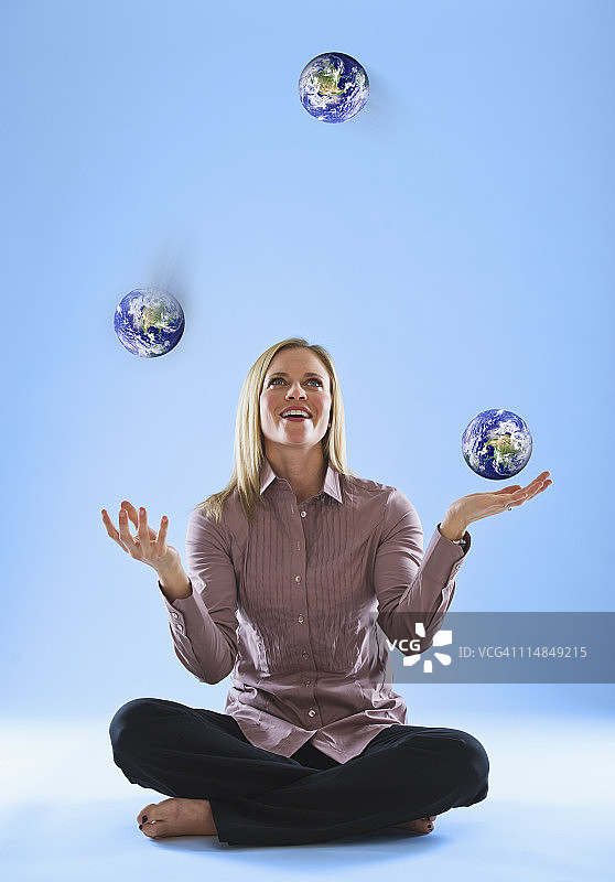 在云端玩杂耍地球仪的年轻女人图片素材