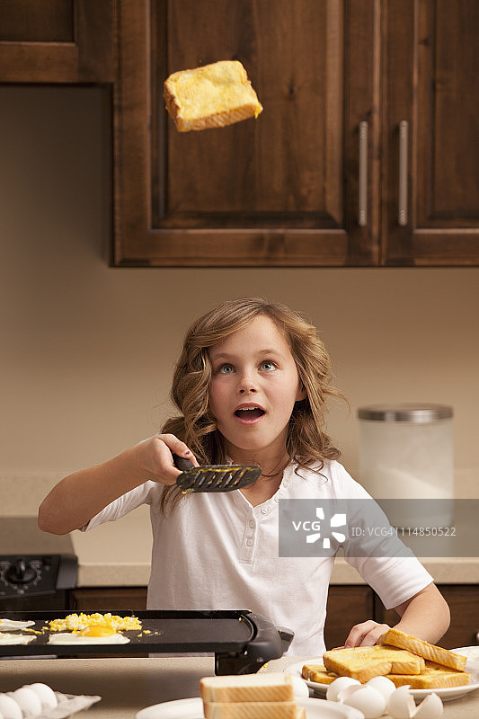 美国犹他州利海，女孩在厨房里翻烤面包图片素材