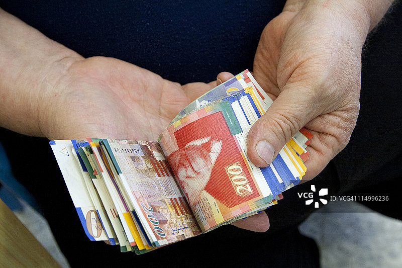 在货币兑换商处清点以色列谢克尔纸币图片素材