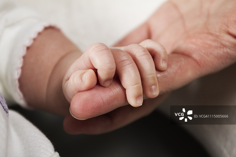 新生女婴抓住妈妈的手指图片素材