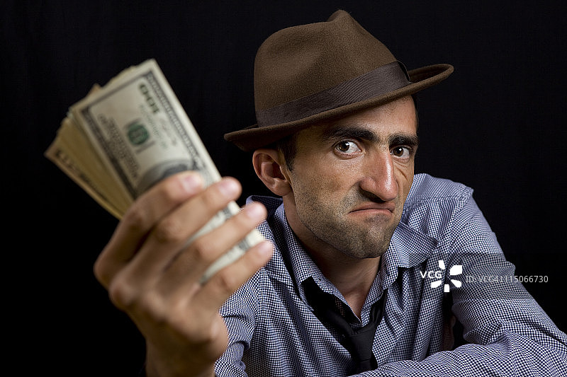 戴着软呢帽，拿着美元钞票的男人照片图片素材