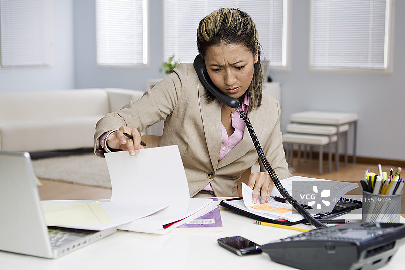 皱眉的混血女商人伏案工作图片素材