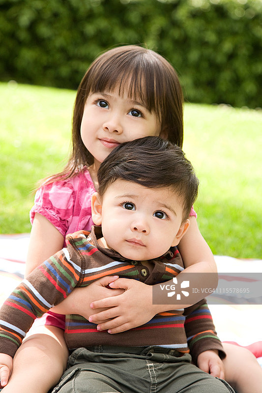 抱着六个月大弟弟的3岁女孩图片素材