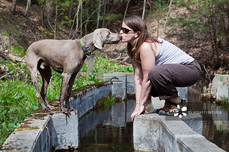 女人和满身泥土的狗亲吻图片素材