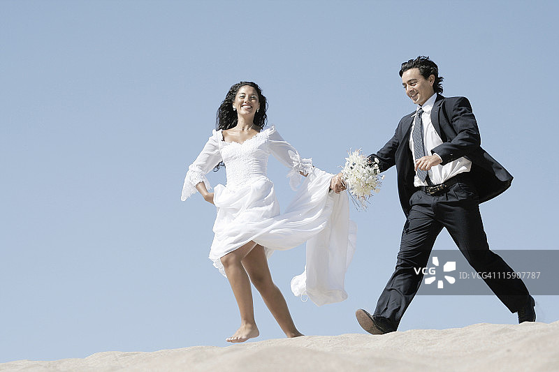 在沙丘中跳跃的新娘和新郎图片素材