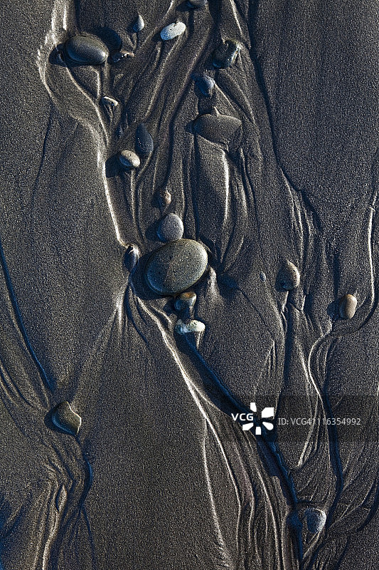 华盛顿州奥林匹克国家公园卡拉洛奇海滩上，水和圆润的鹅卵石在沙滩上形成抽象图案图片素材