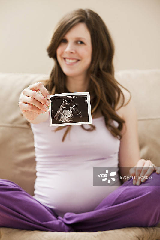 美国犹他州莱希，展示未出生婴儿CT影像的年轻孕妇图片素材
