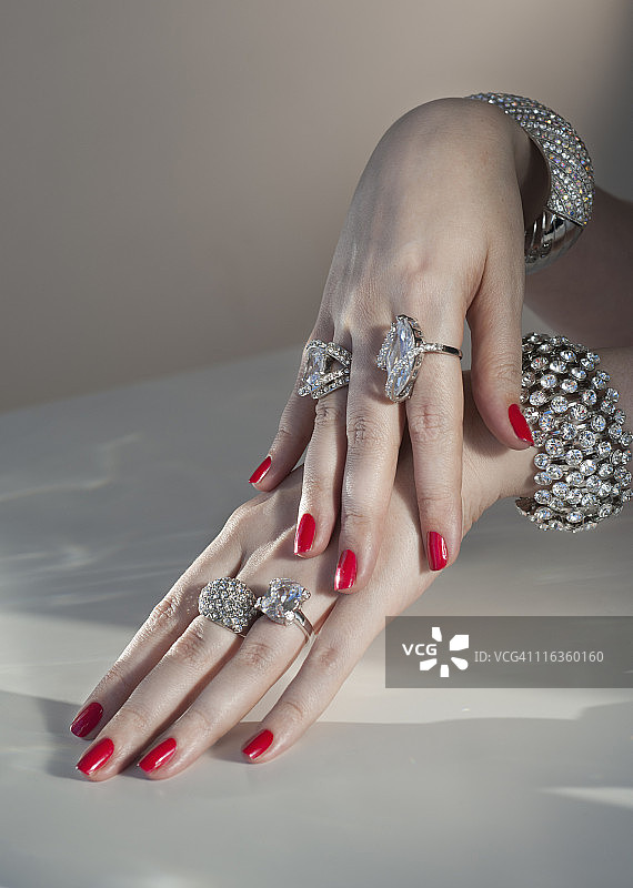 女性涂着红色指甲油的手和钻石首饰（特写）图片素材