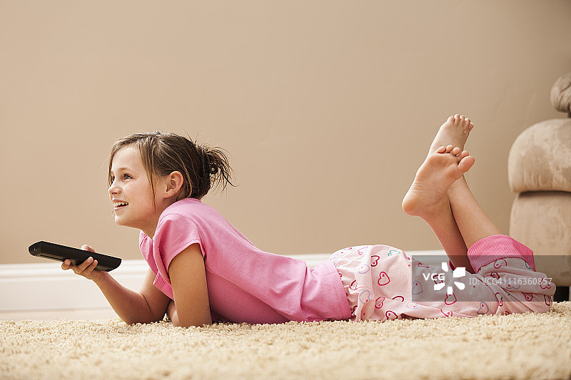 美国犹他州Lehi：躺在地板上拿着遥控器的女孩（10-11岁）图片素材