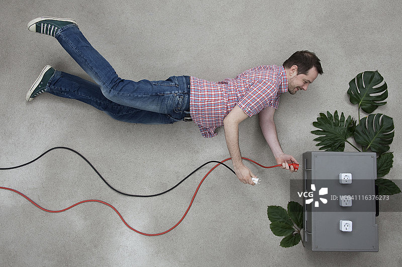 中年男人拿着插头靠近电源插座图片素材