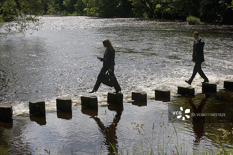 男人使用手机，女人发短信，过河图片素材