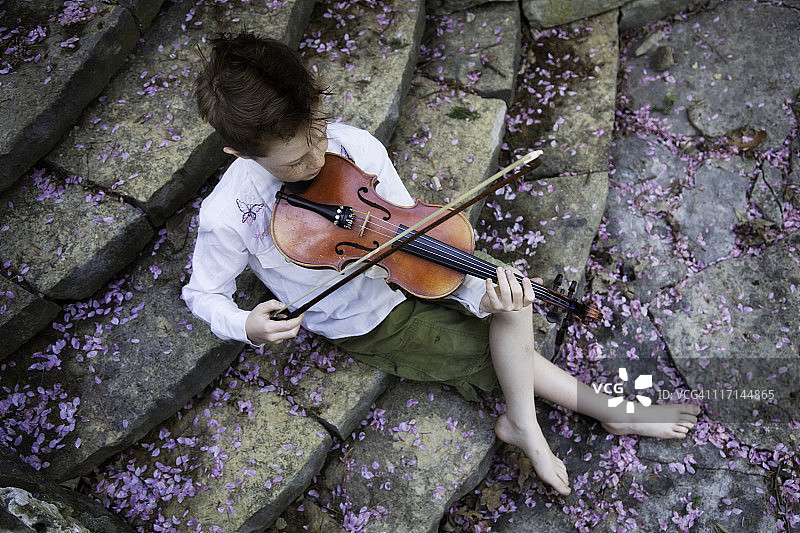 在石阶上拉小提琴和花瓣的儿童图片素材
