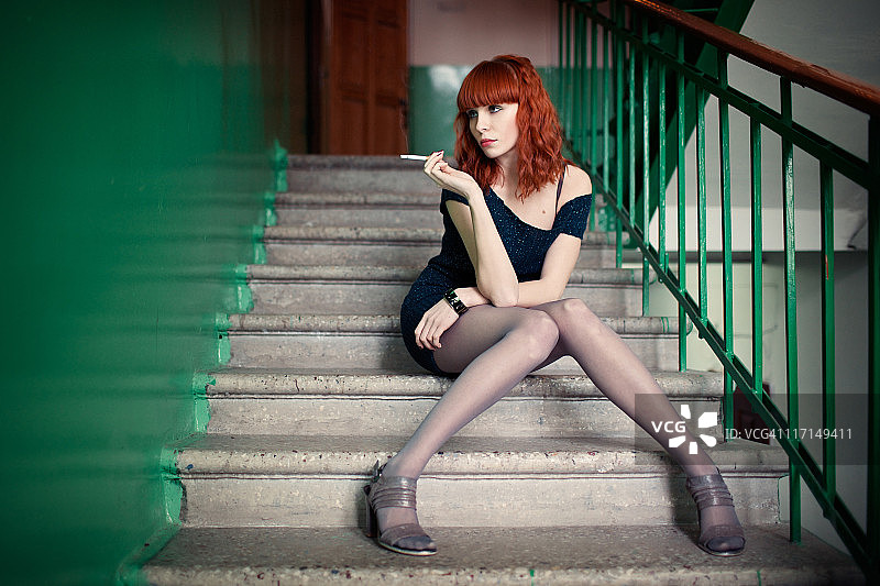 坐在楼梯上抽烟的庸俗红发女孩图片素材