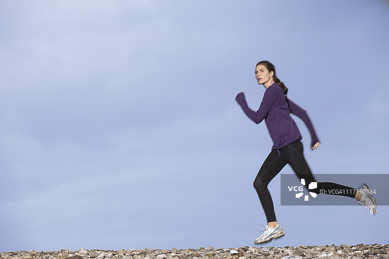 女人在鹅卵石海滩上慢跑图片素材
