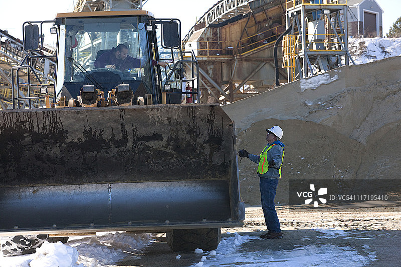 工程师在传送带前与前端装载机司机咨询图片素材
