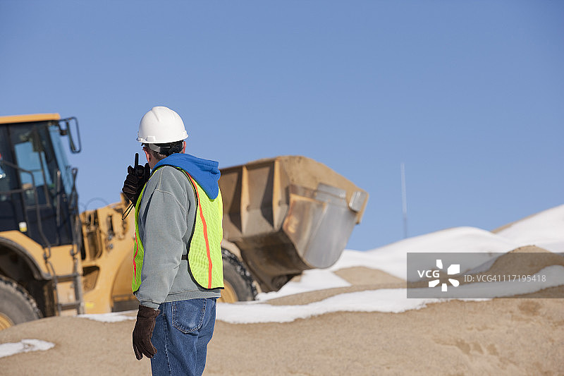 工程师用对讲机指挥施工现场的装载机图片素材