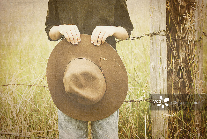 用指尖拿着帽子的农场男孩图片素材
