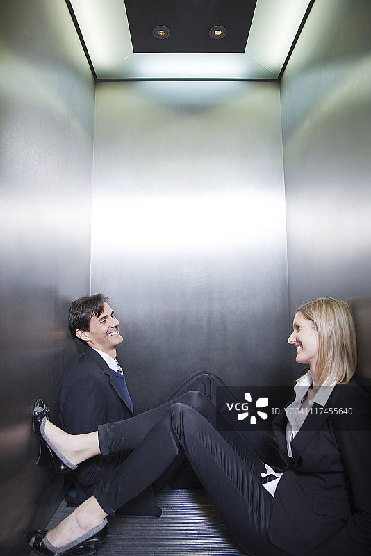被困在电梯里坐在地上聊天的商务人士图片素材