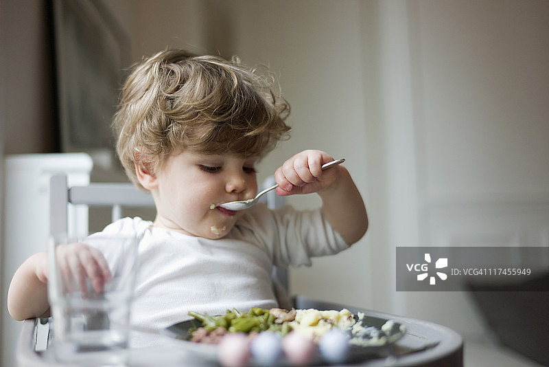幼儿男孩自己用勺子吃饭图片素材