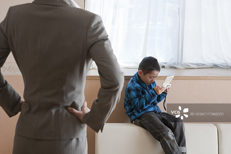 儿子玩掌上游戏机，母亲责备图片素材